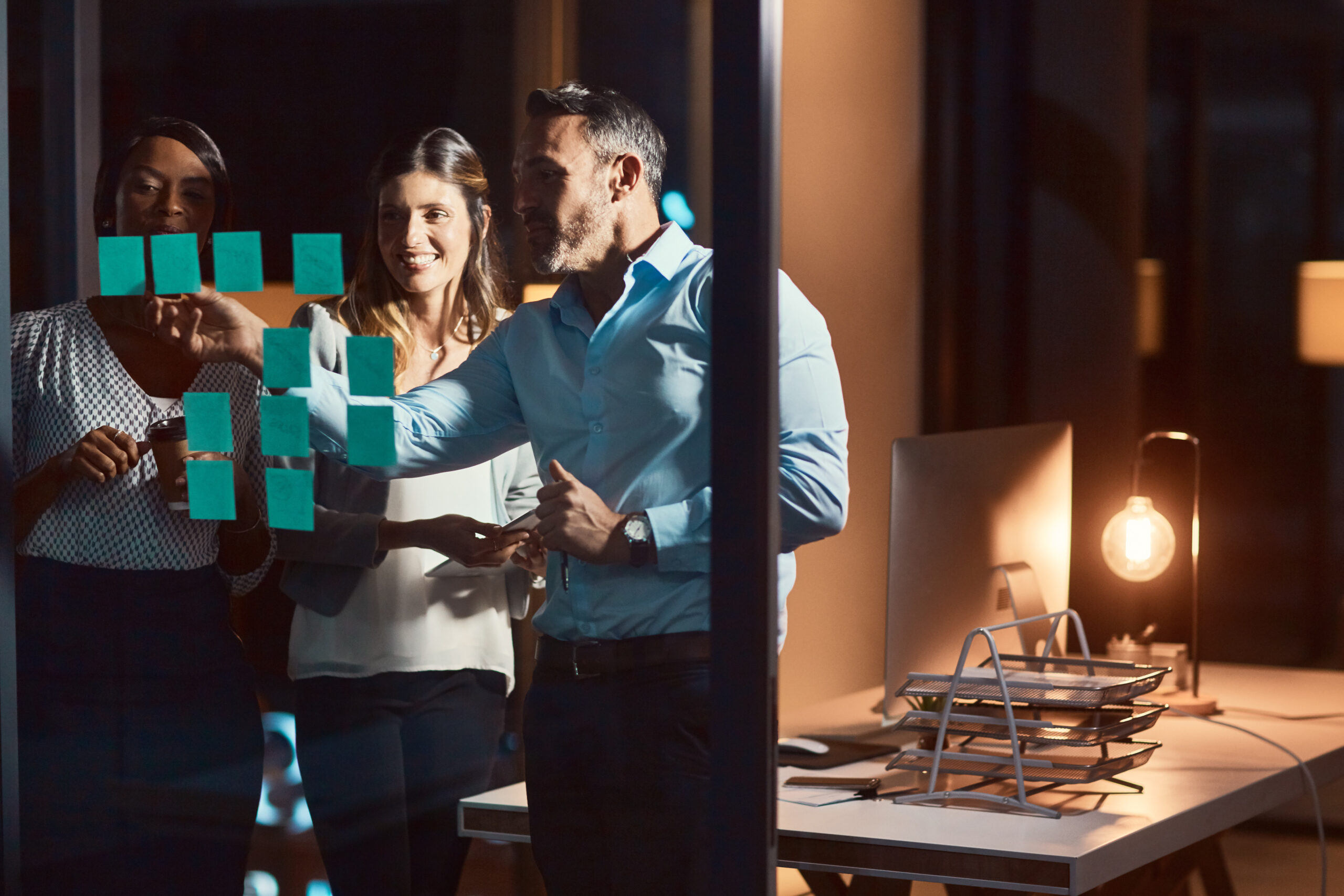 Equipo empresarial implementando una estrategia de marketing digital en una oficina oscura.